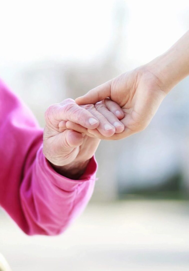 A younger hand holding an older person's hand in a caring gesture